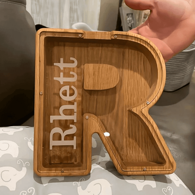 Personalized wooden letter 'R' piggy bank for kids, designed to promote savings and financial awareness.