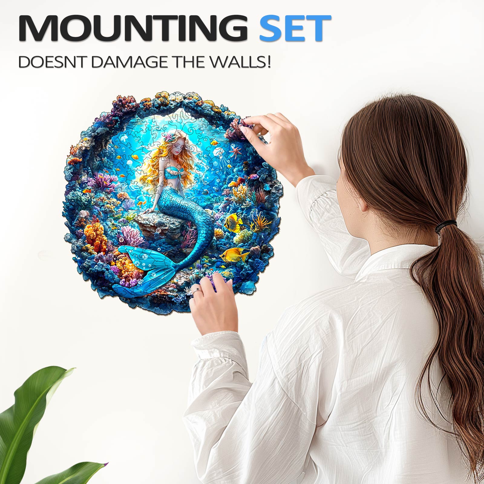 Woman mounting a 3D mermaid wooden jigsaw puzzle on the wall, showcasing easy, damage-free installation.