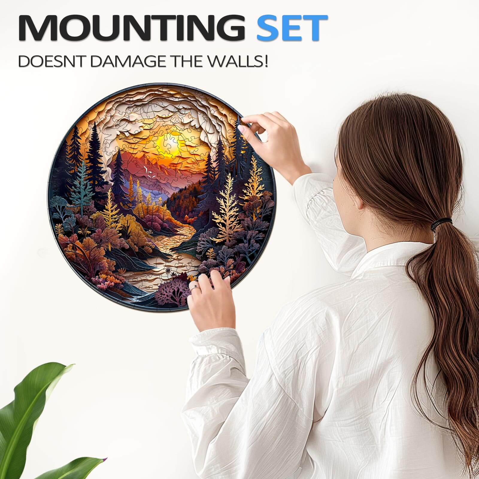 Woman installing a 3D Sunset Forest wooden jigsaw puzzle with a mounting set that doesn’t damage the walls.