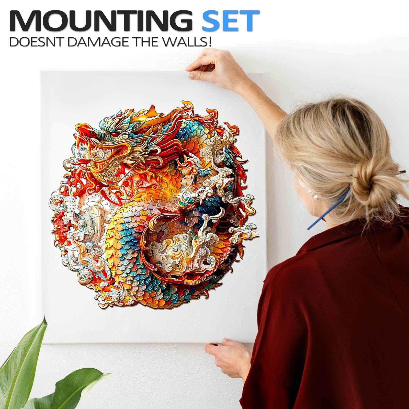 Person hanging a colorful 3D Chinese dragon artwork using a wall-safe mounting set.