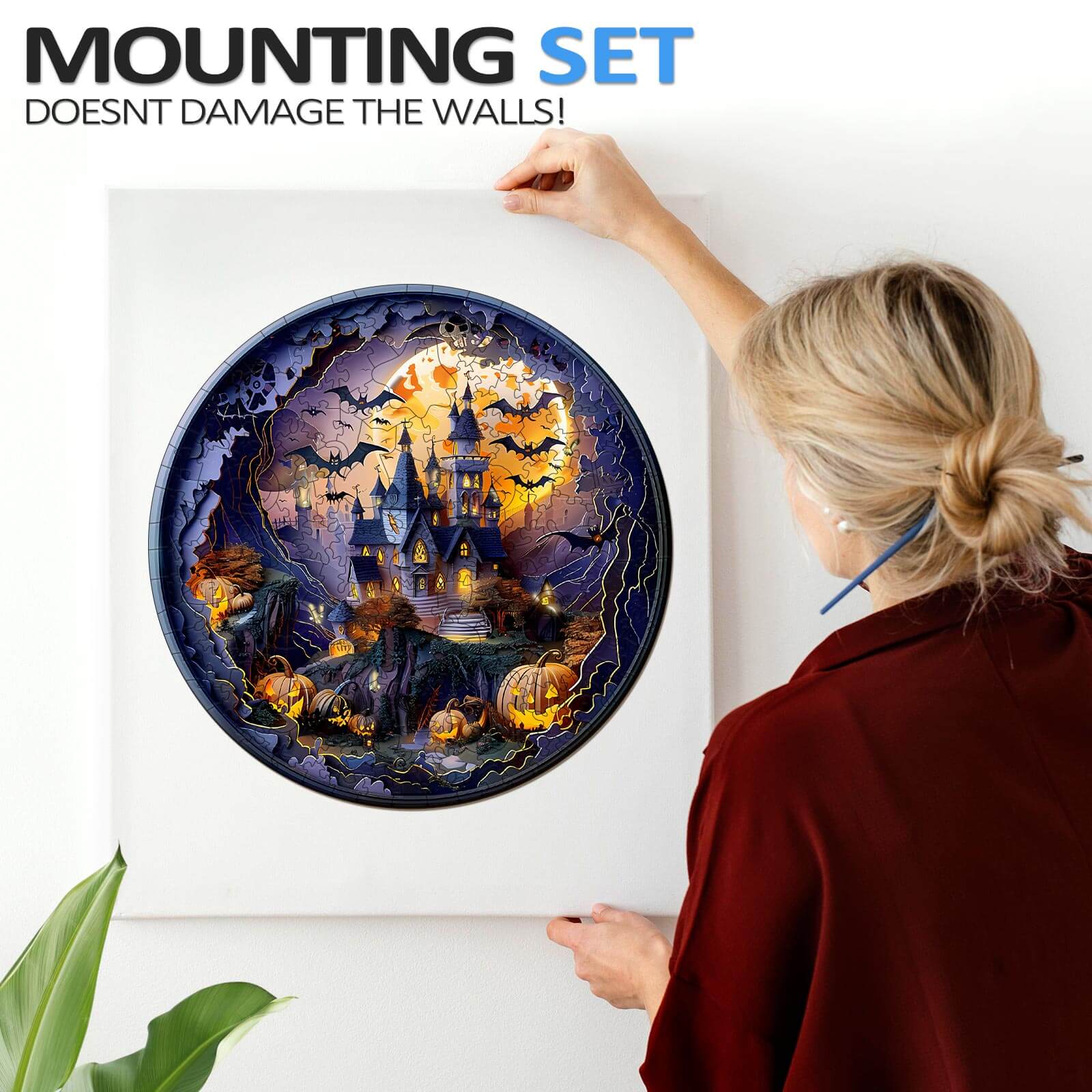 Person hanging a 3D Halloween Castle wooden jigsaw puzzle with a mounting set that doesn't damage the walls.