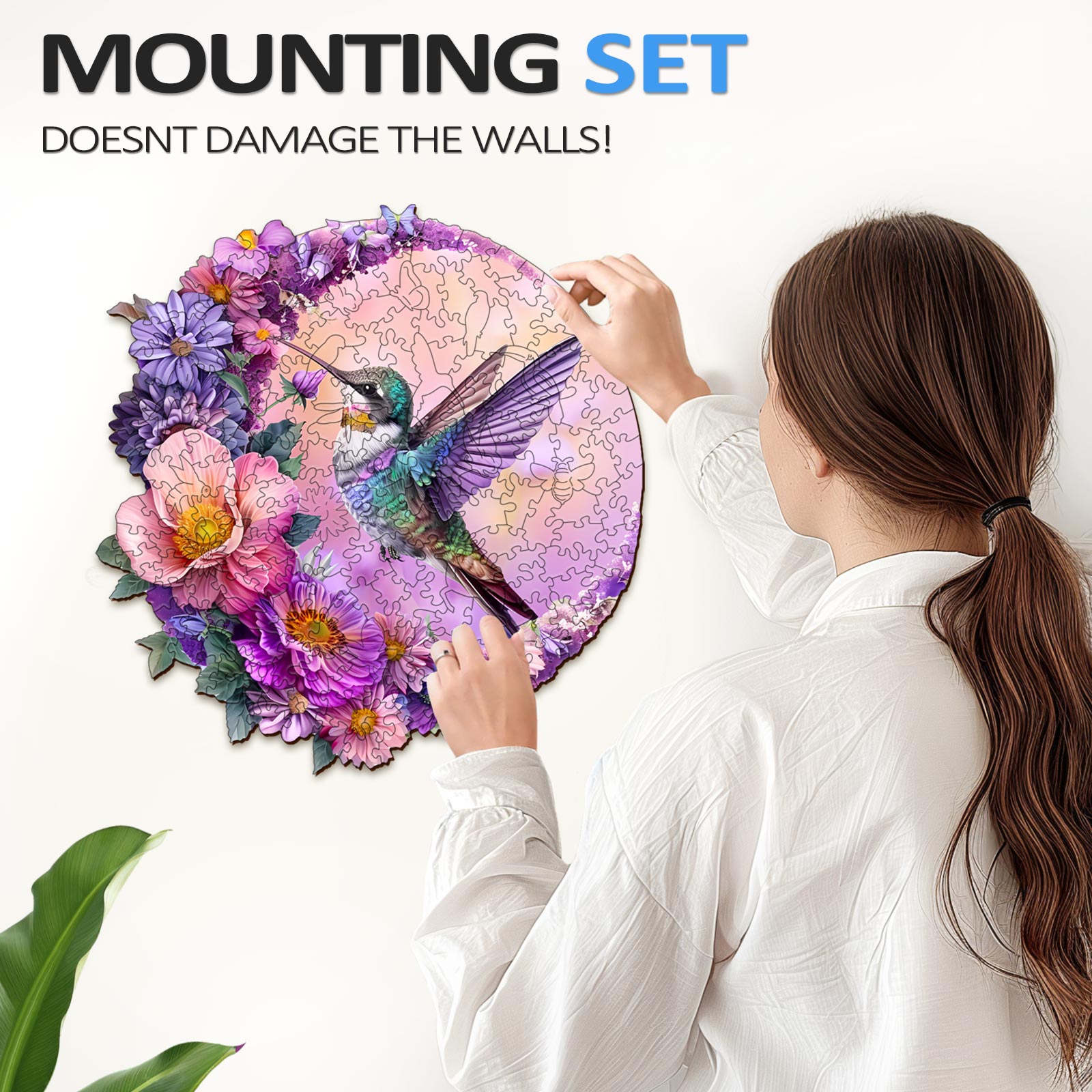 Person mounting a Hummingbird and Moon wooden jigsaw puzzle with flowers on a wall, promoting focus and mental engagement.