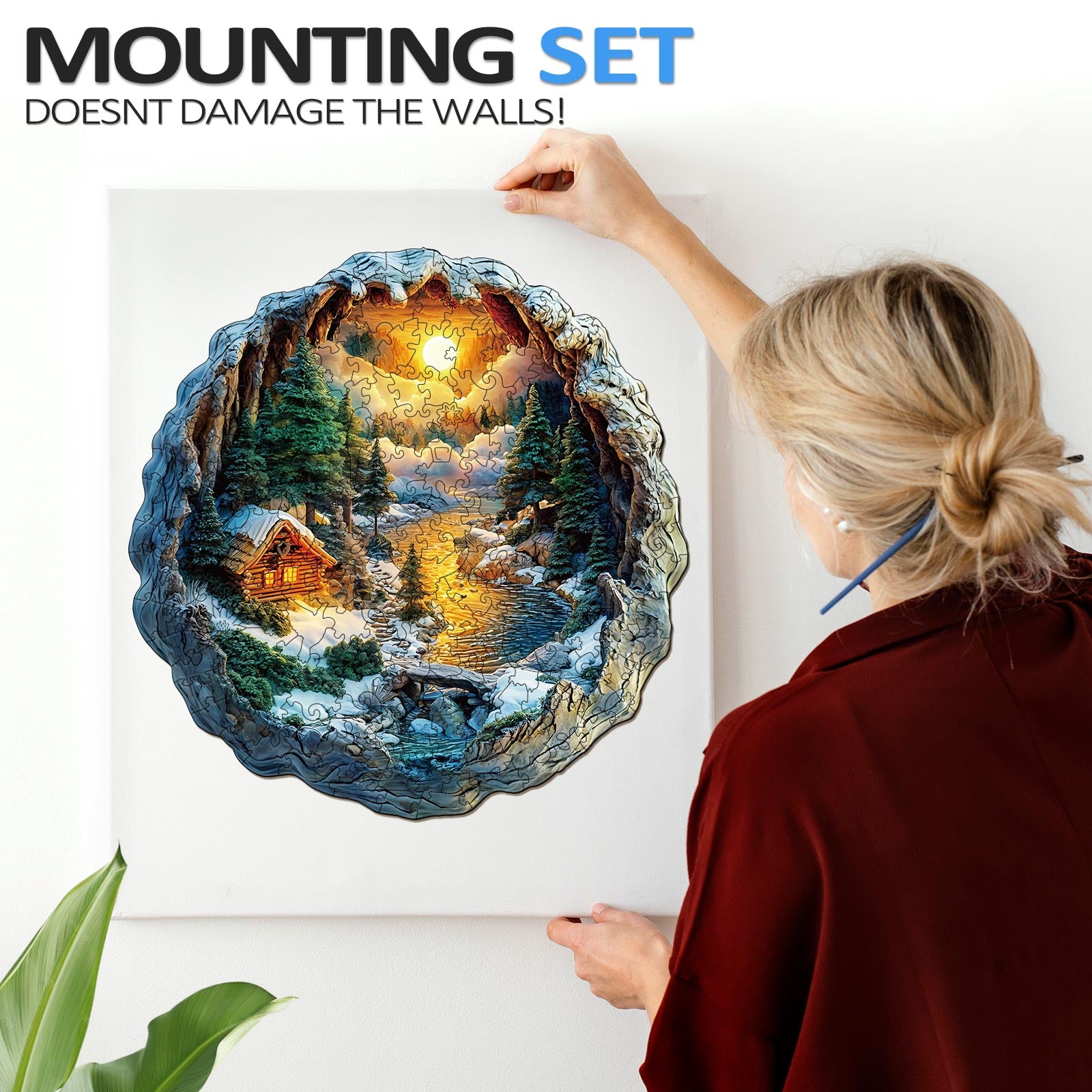 Person hanging a 3D Winter Scene jigsaw puzzle on a wall using a mounting set that doesn't damage walls.