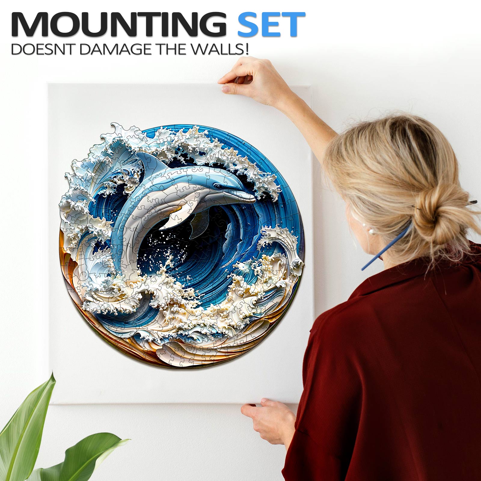 Woman mounting a 3D Dolphin-1 wooden jigsaw puzzle on a wall, showcasing its unique design without damaging the surface.