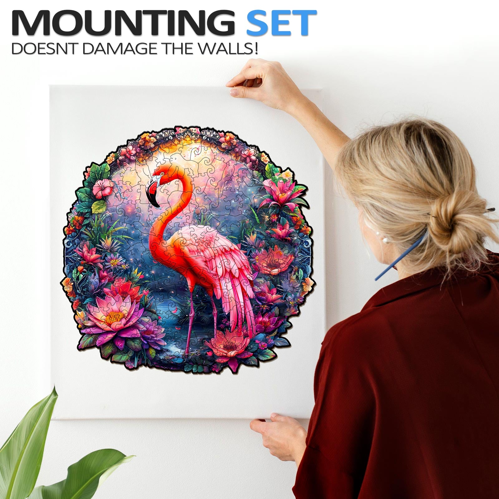 Person mounting a colorful Elegant Flamingo jigsaw puzzle framed on the wall, showcasing vibrant art and involved puzzle solving.