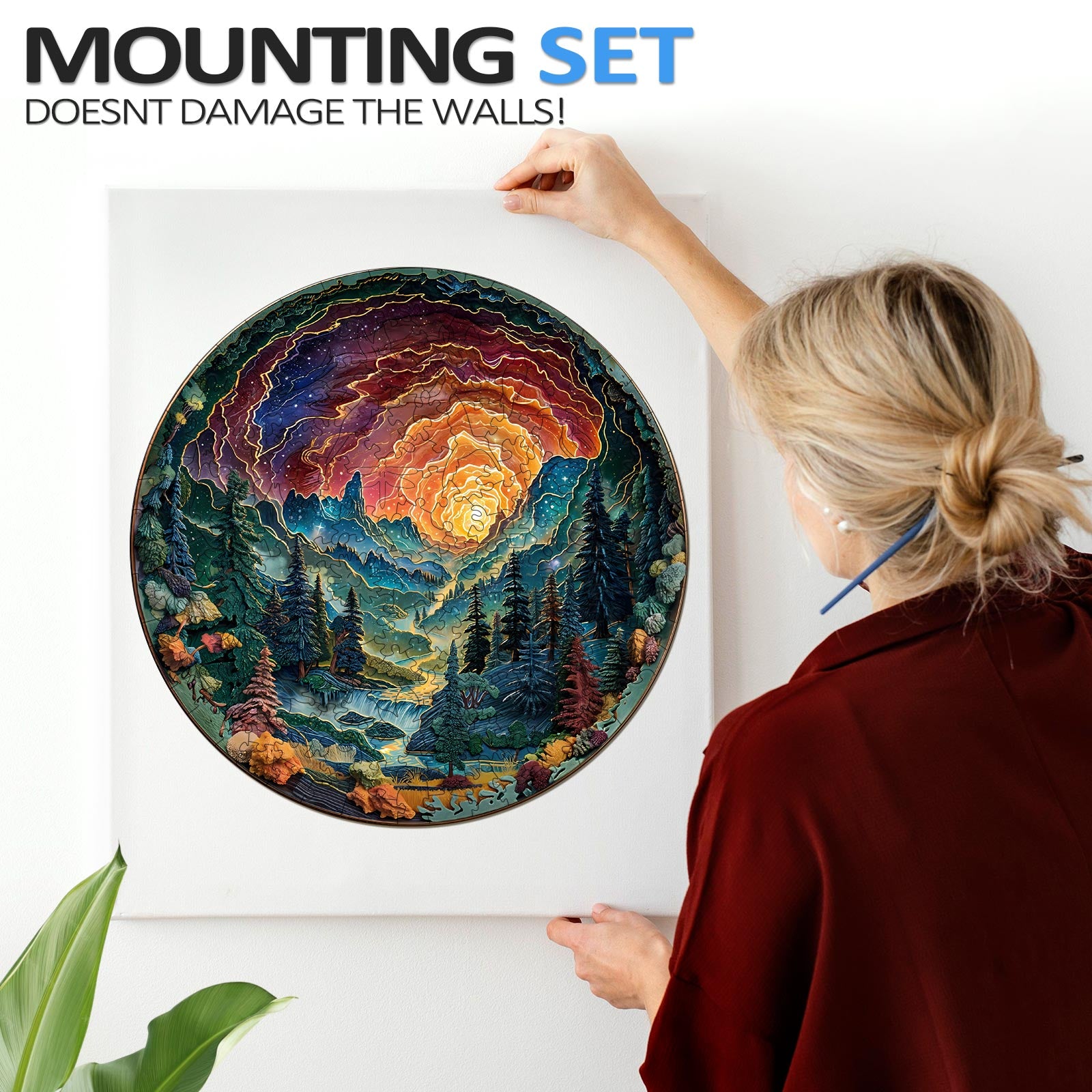 A woman elegantly hanging a 3D cave sky jigsaw puzzle on the wall using a damage-free mounting set.