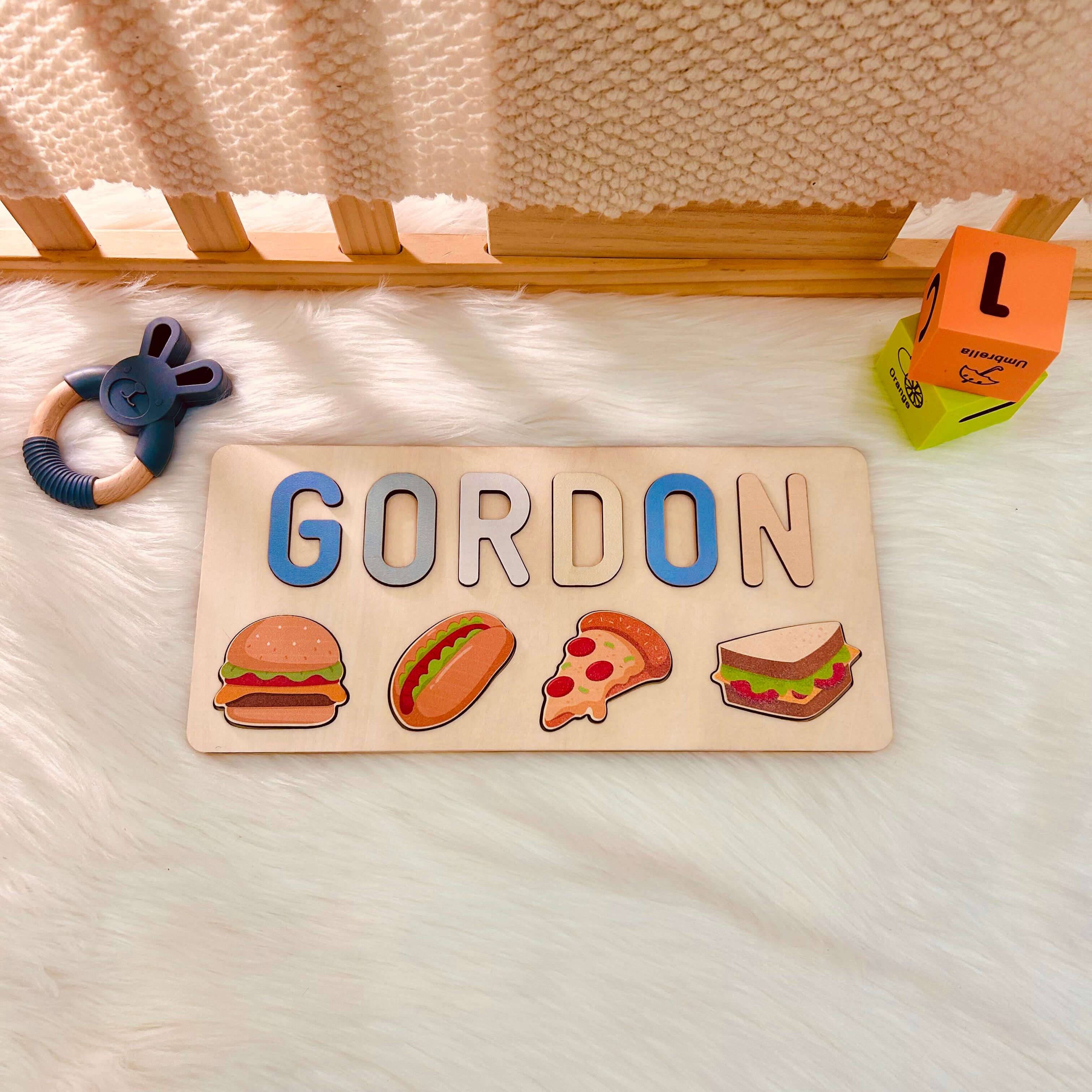 Personalized wooden baby name puzzle with food icons, featuring the name GORDON in colorful letters.