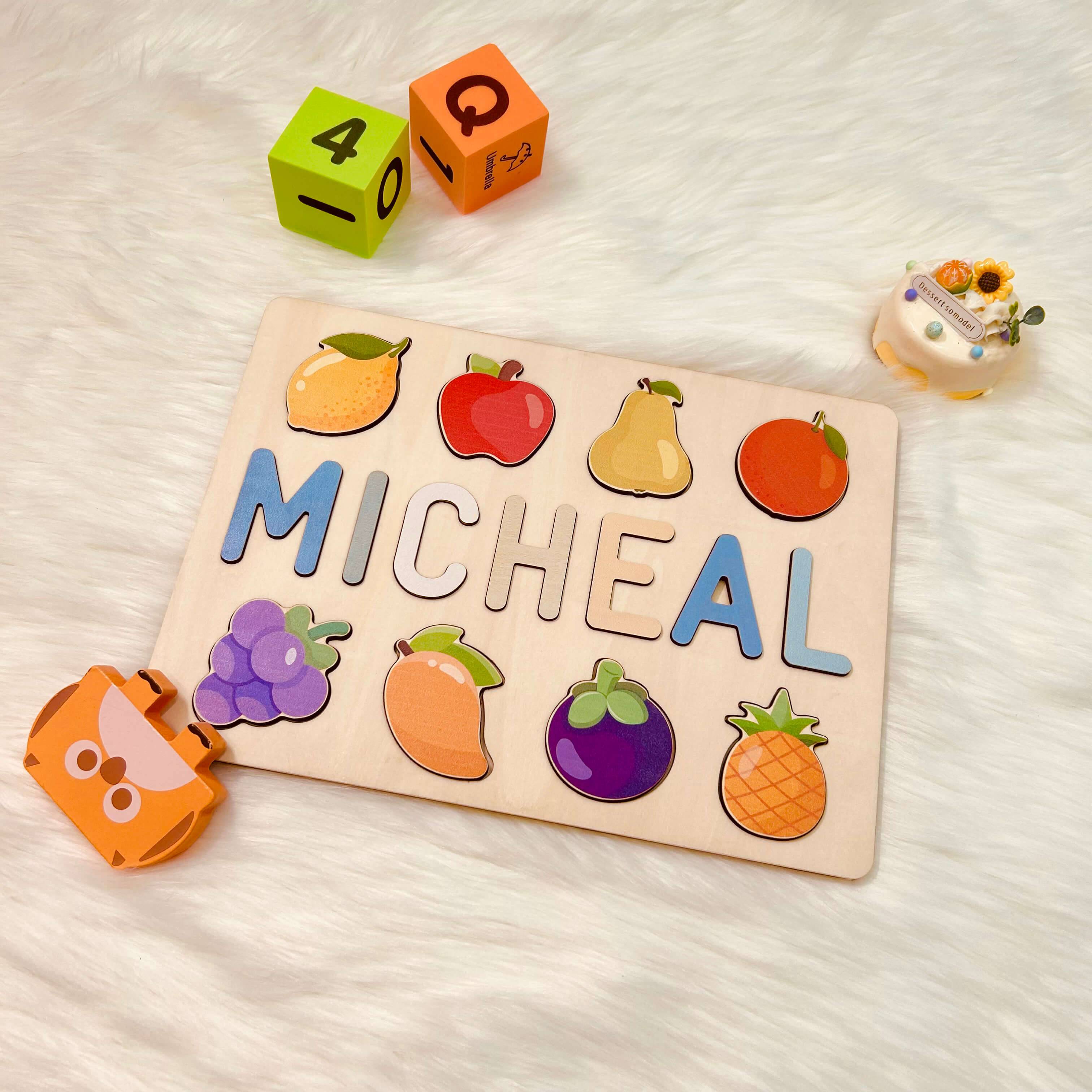 Personalized wooden baby name puzzle with fruit, featuring the name 'Micheal' and colorful blocks.
