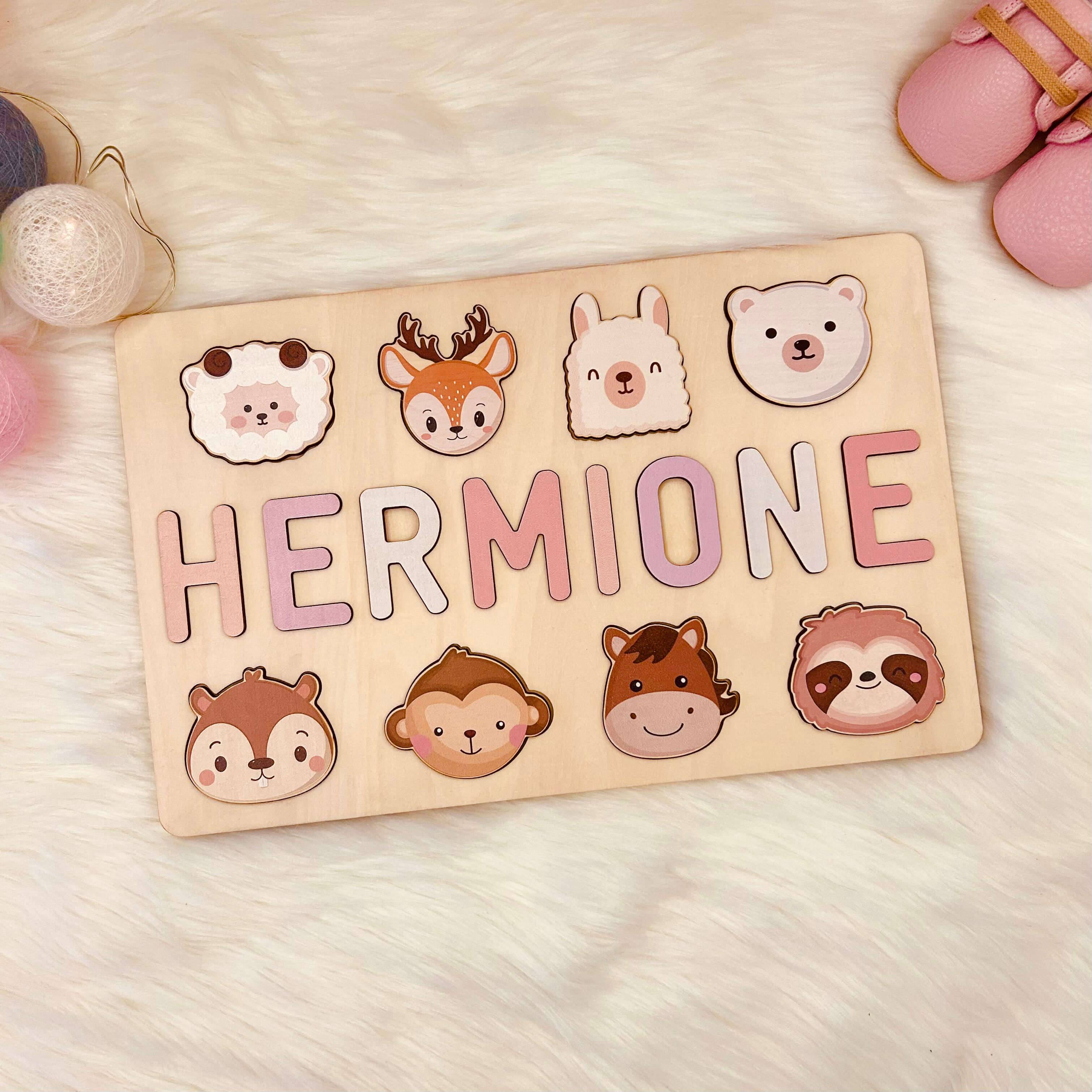 Personalized wooden baby name puzzle with animal graphics, featuring the name 'HERMIONE' in pastel colors.