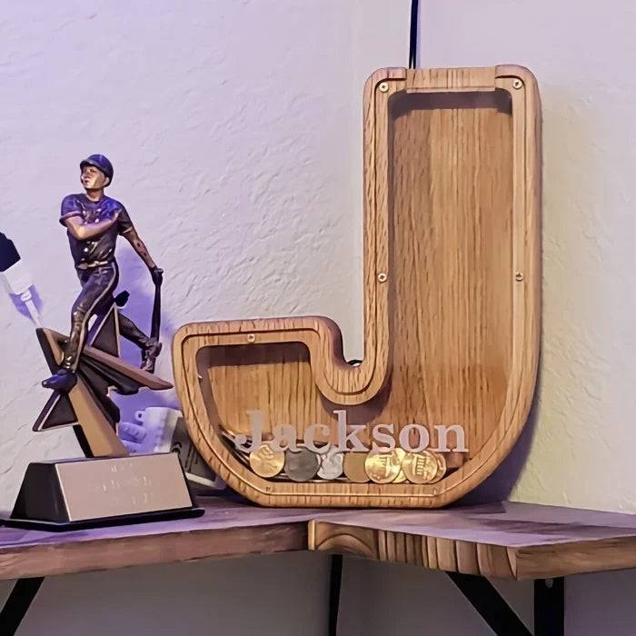 Personalized wooden letter piggy bank 'J' for kids, designed for saving coins and teaching financial awareness.