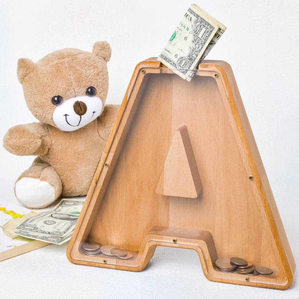 Personalized wooden letter piggy bank shaped like 'A' with a teddy bear, bills, and coins for kids.