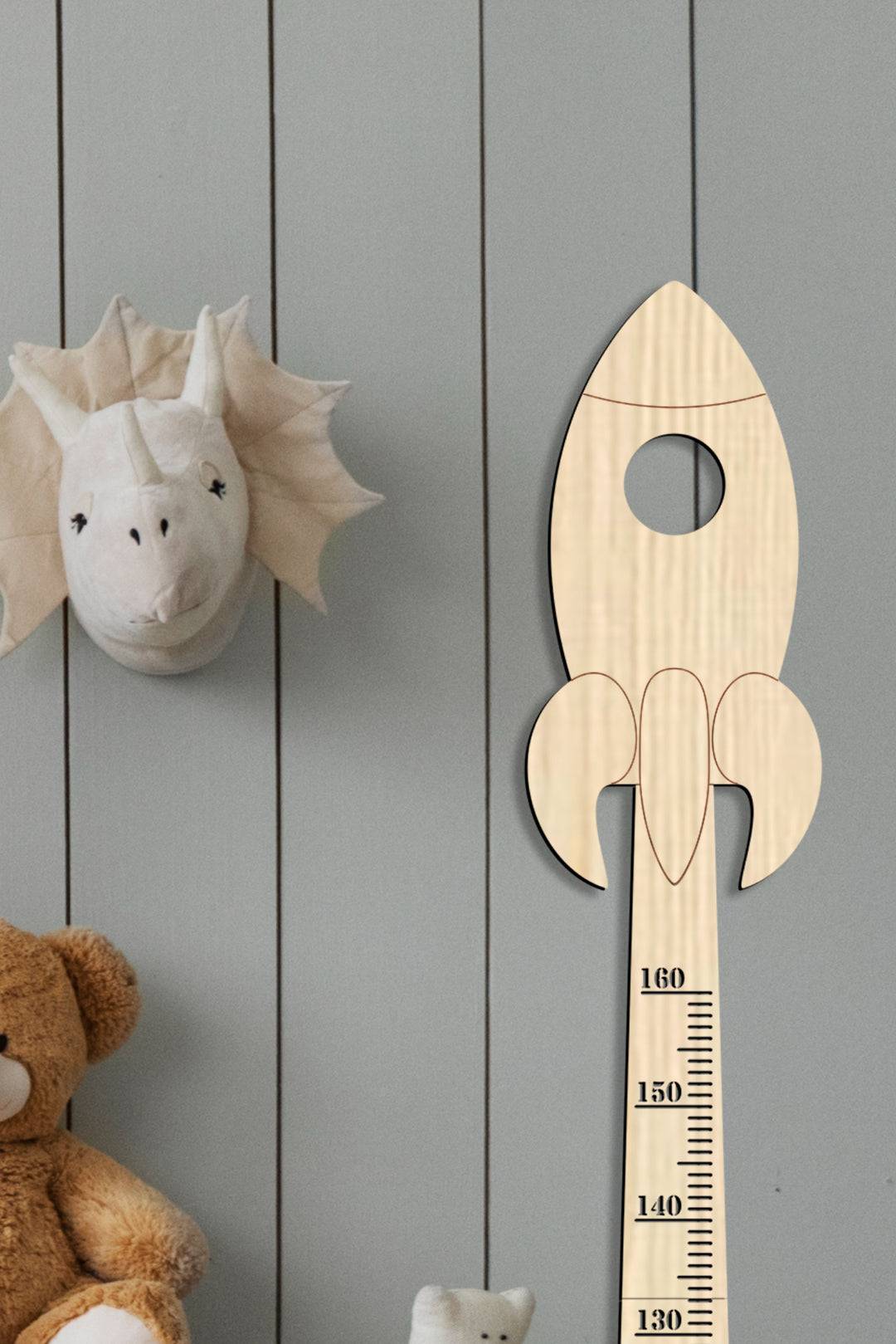 Personalized wooden rocket growth chart hanging on a nursery wall, perfect for tracking kids' height.