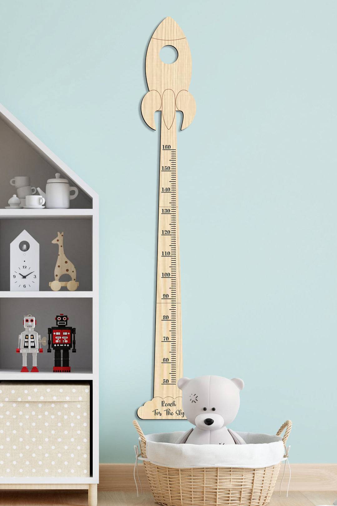 Personalized wooden rocket growth chart nursery decor with a bear toy in a stylish room.