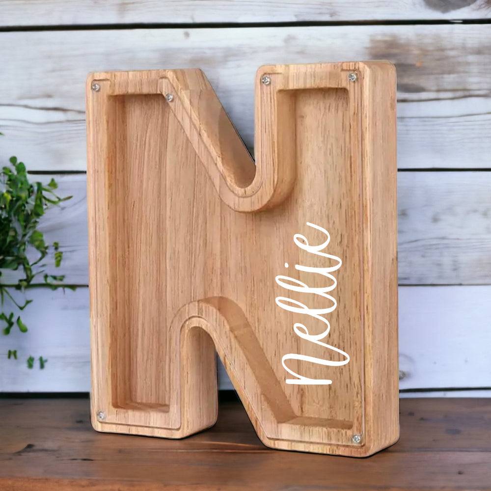 Personalized wooden letter 'N' piggy bank for children, designed for saving coins and teaching money management.