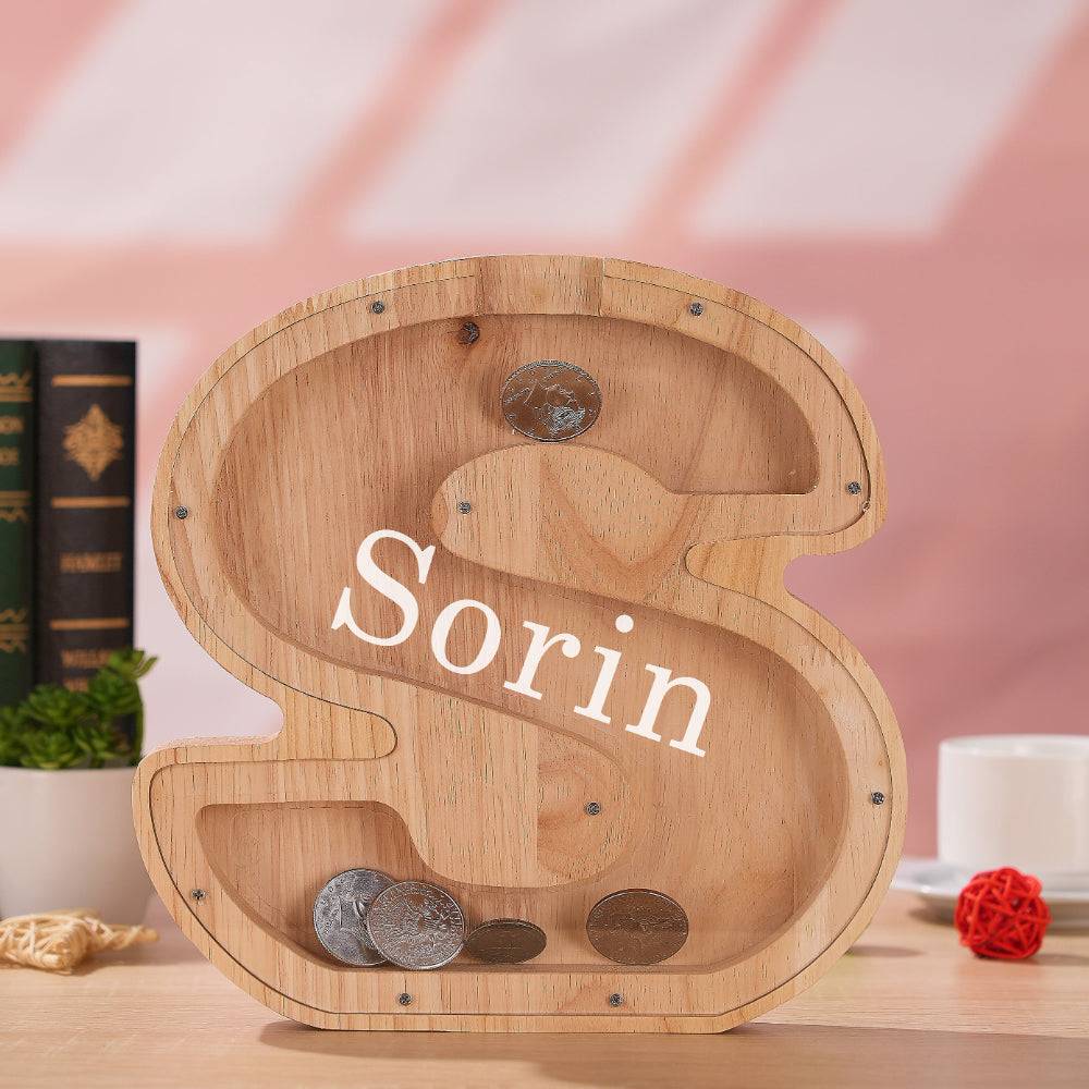 Personalized wooden letter piggy bank shaped as 'S' with coins, perfect for teaching kids about saving.